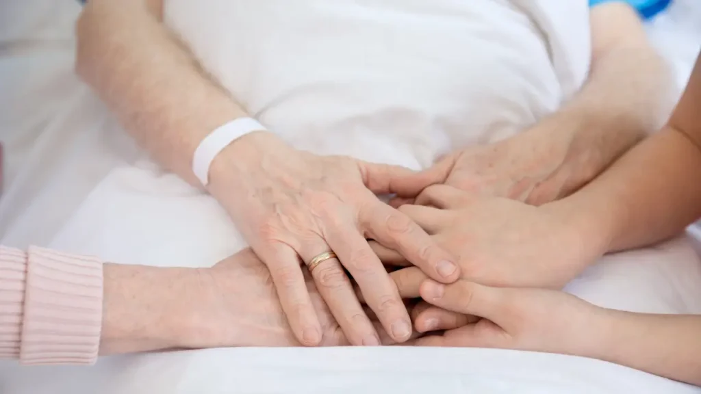 Family members holding hands with a hospitalized patient, showing emotional support and compassion